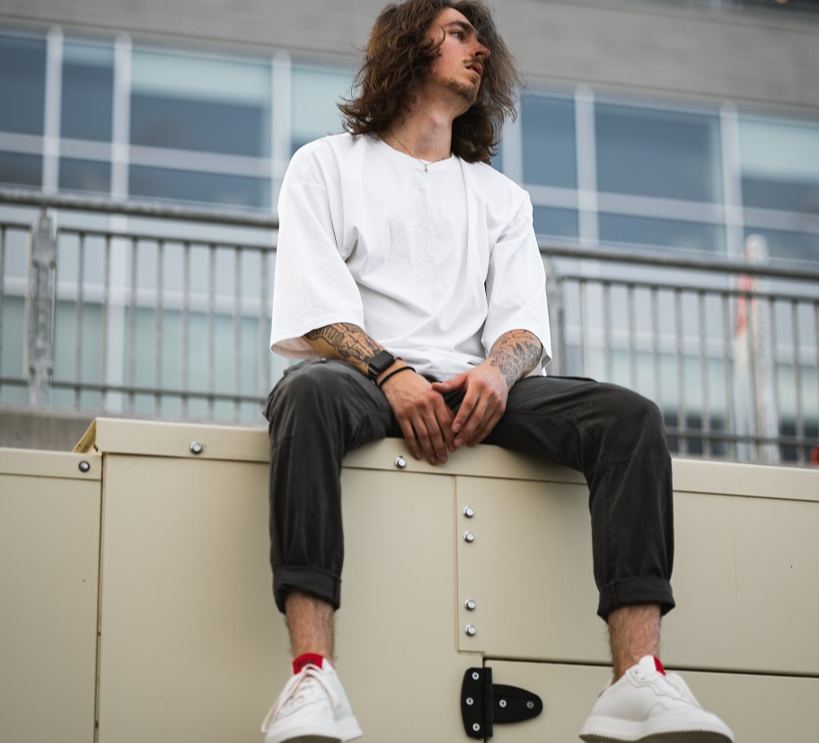 picture of a men sitting in front a building wearing casual clothes 